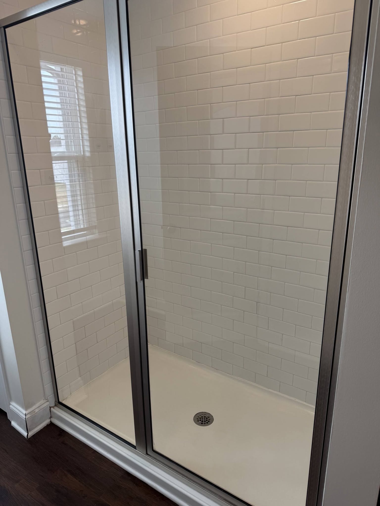 A shower cleaned to clear glass and bright white tile