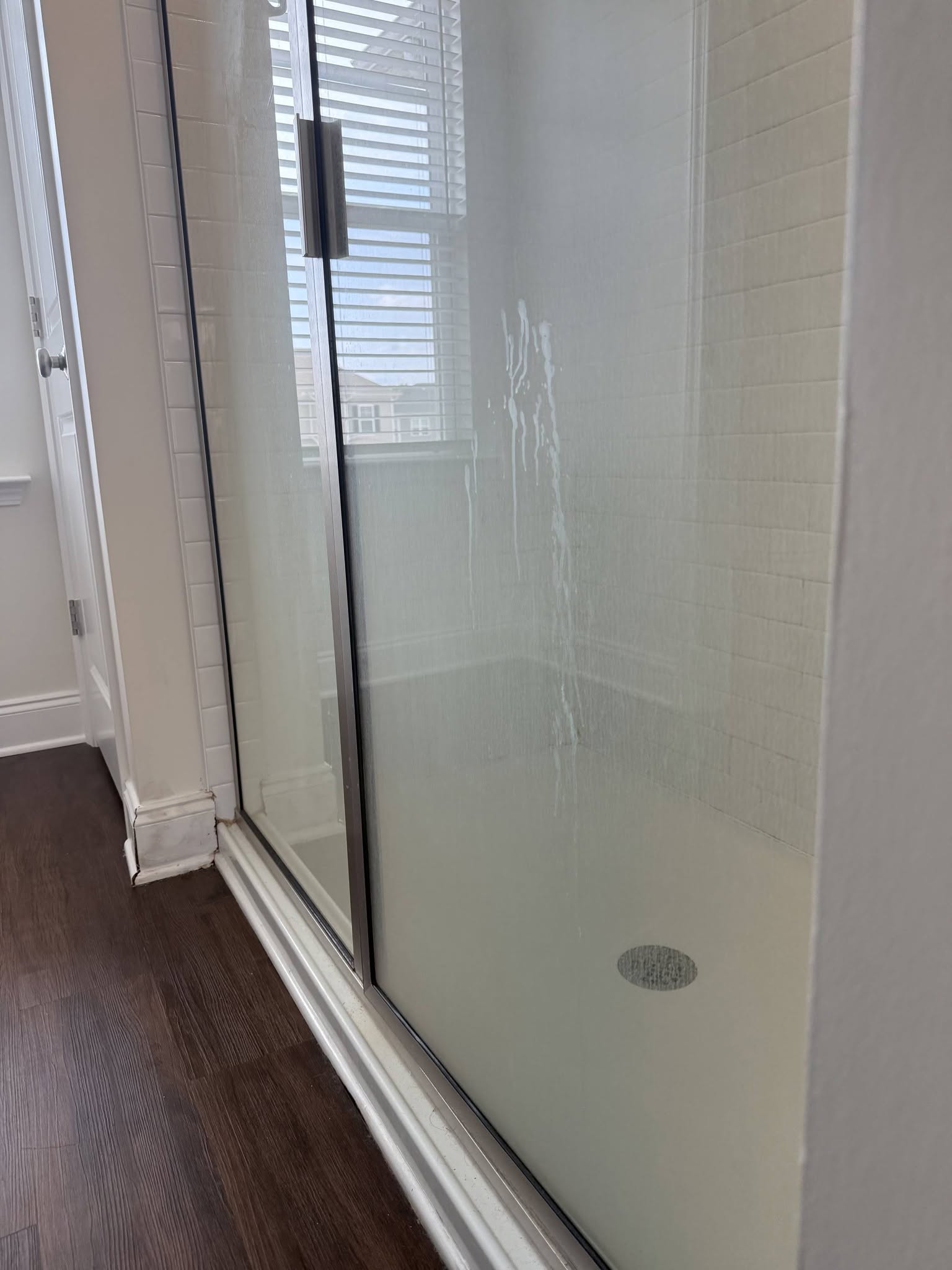 Shower glass clouded with soap scum and hard water before cleaning