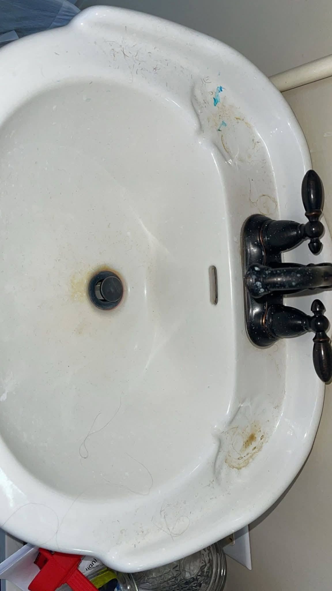 A bathroom sink with rust staining, hair and grime before cleaning