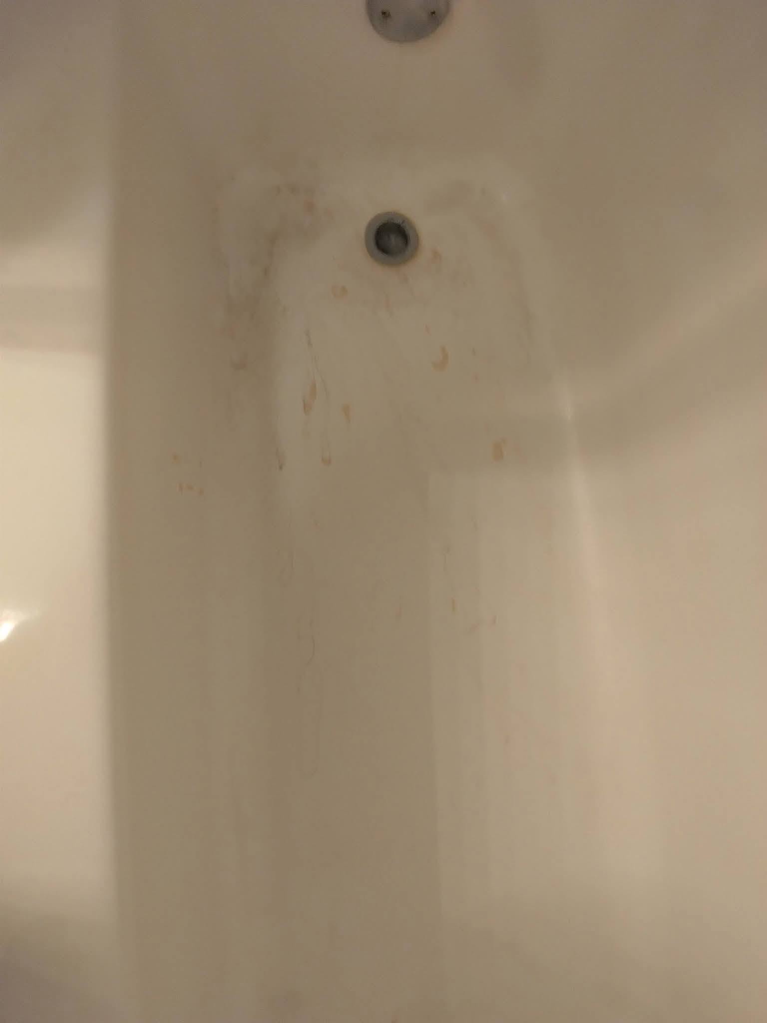 A bathtub with rust streaks and staining before cleaning